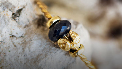 Twisted gold bangle with onyx bead and flower bead in gold