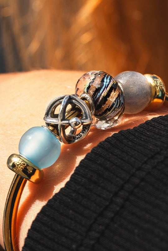 Golden cosmic-themed bangle with intricate celestial patterns, adding a touch of mystique and elegance to your accessory collection featuring a light blue agate to give you a sense of inner peace